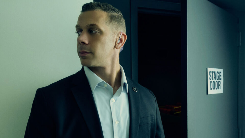 Security team in action captured in a lifestyle photography session, Professional security guard on duty in a lifestyle photo shoot, Lifestyle photography depicting a security briefing for an event, Security personnel patrolling a shopping center in a lifestyle image, Close-up lifestyle shot of security communication equipment in use, Security guards ensuring safety at a private event, captured in lifestyle photos, Lifestyle image of a security professional escorting a client, Security team coordination captured in a dynamic lifestyle photograph, Vigilant security presence at a public gathering, Lifestyle photography showcasing a security company's commitment to safety