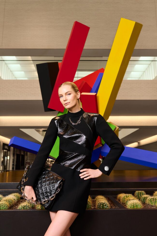 Los Angeles fashion photographer, architectural fashion image of a model in a black structured outfit holding a designer handbag in front of a colorful sculpture, campaign photo for fashion brands, accessories, lookbooks, and digital marketing.