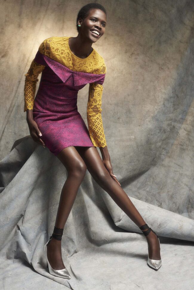 Los Angeles fashion photographer, colorful studio fashion image of a model in a yellow lace and magenta patterned dress seated against a textured backdrop, editorial campaign photo for fashion brands, lookbooks, and digital marketing.