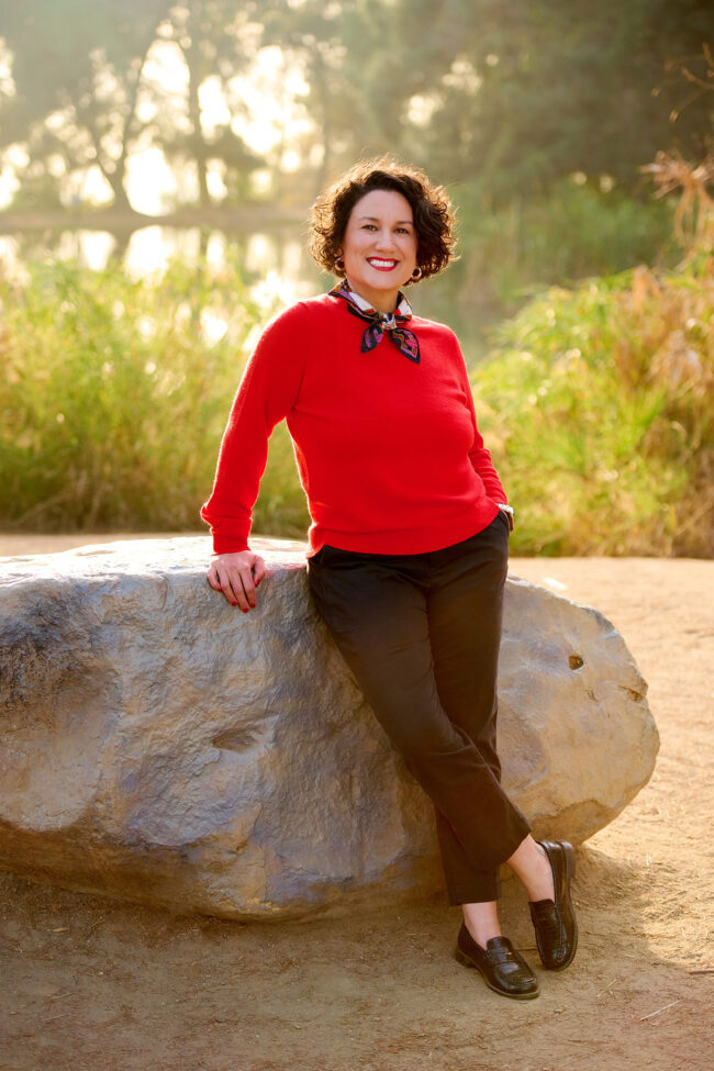 Social media photographer in Los Angeles, outdoor personal brand portrait of a woman in a red sweater near greenery and water, lifestyle content photo for Instagram, websites, and digital marketing.