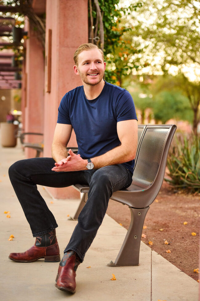 Social media photographer in Los Angeles, casual personal brand portrait of a man seated outdoors in a blue t-shirt and boots, lifestyle content photo for Instagram, websites, and digital marketing.
